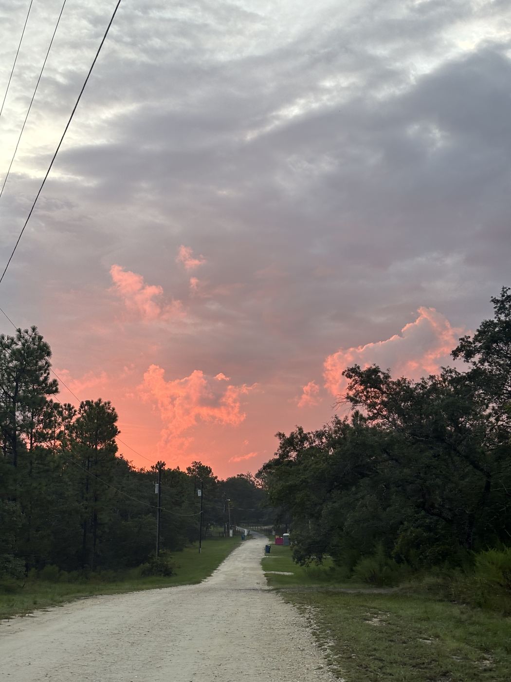 A back road at sunset under a coral sky